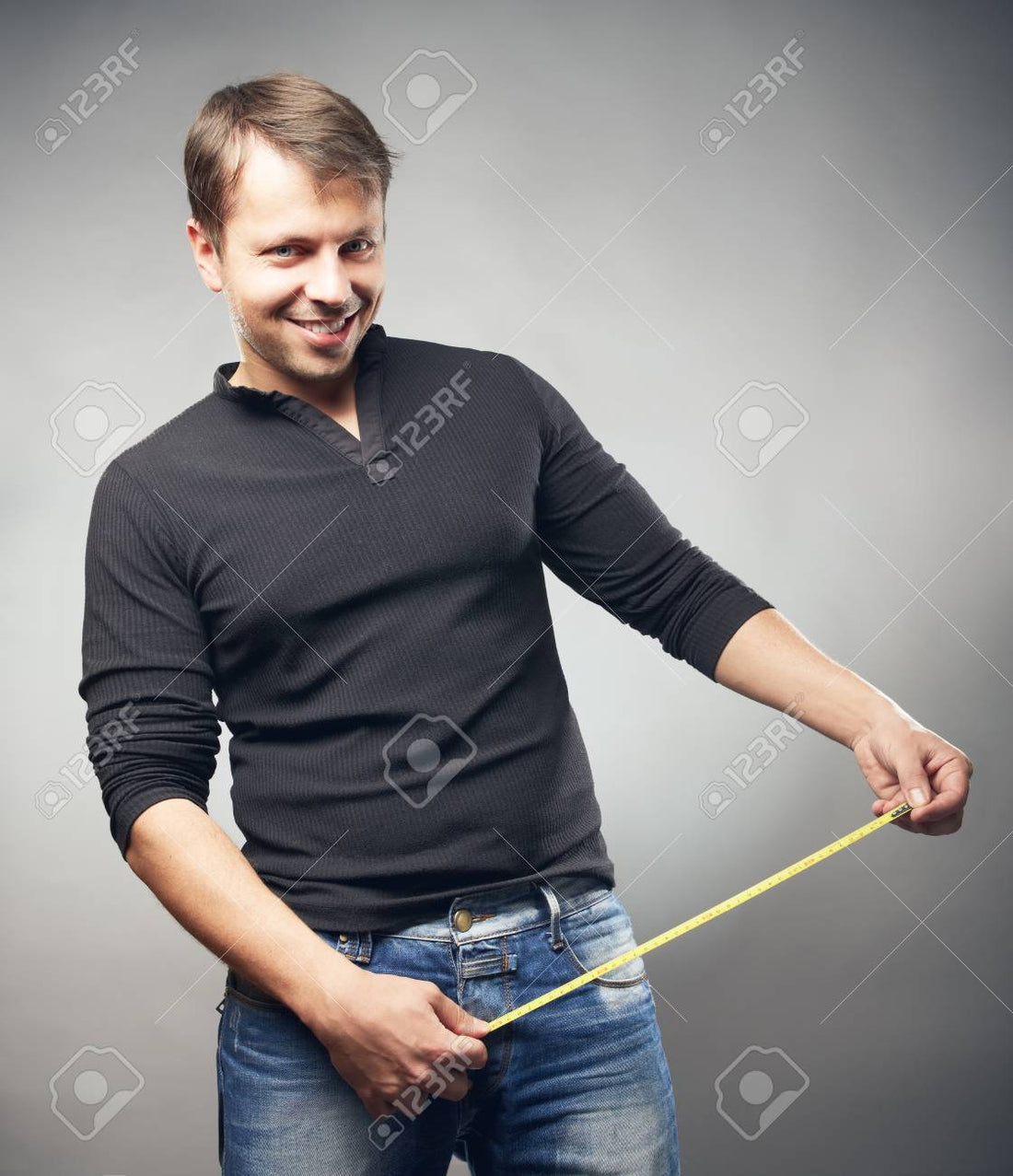 Man wearing Black Shirt holding a Tape Measure in a Funny Manner